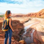 Young woman looking at beautiful landscape. Nature of Morocco view from above. Traveler girl stands on a rock looks up at the valley of Ounilla Mujeres Viajando Solas en Marruecos: Consejos y Experiencias